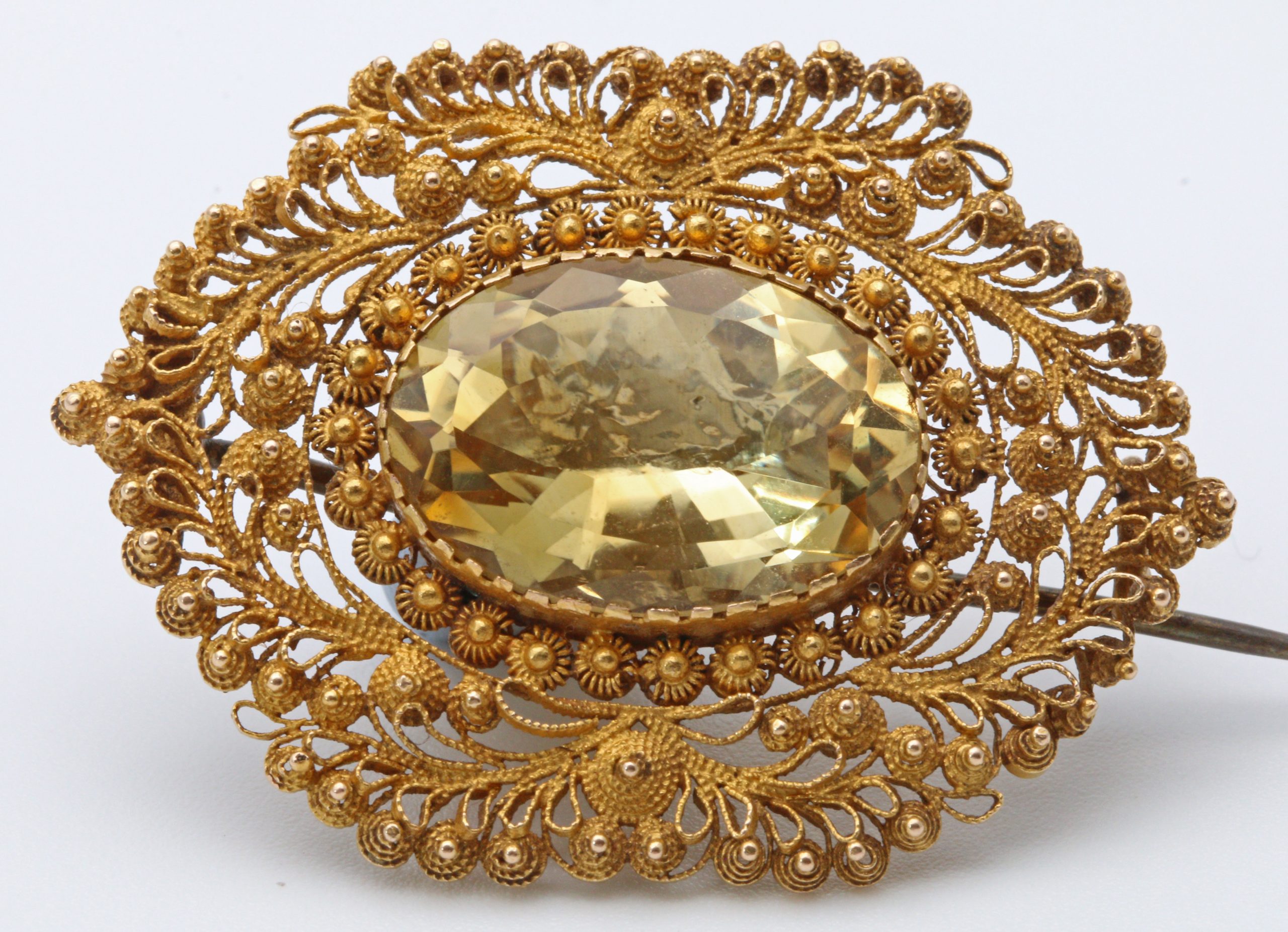Oval citrine brooch surrounded by intricate gold cannetille scrollwork, dated circa 1835.
